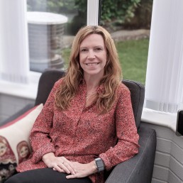 Image of Joanne Brown from Evolve Counselling smiling and sitting in chair.
