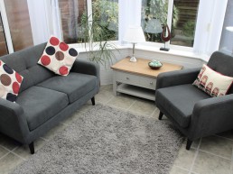 First image of session room at Evolve Counselling showing chair, table, sofa, lamp and cushions.