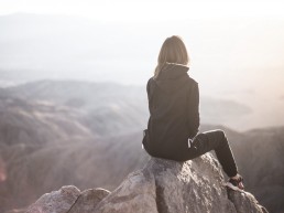 Image of woman at the top of a mountain looking into distance to signify that a person can succeed with any goal they have set themselves.